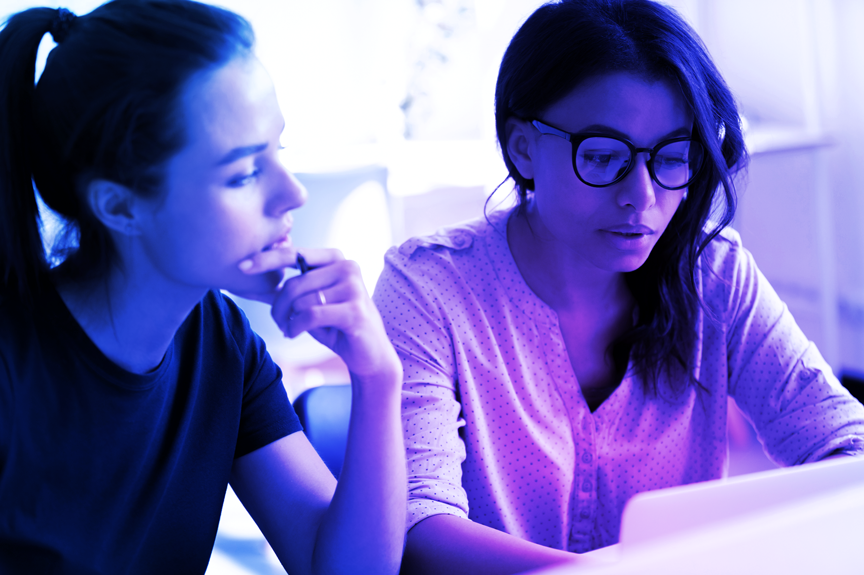 Two people viewing the Crane Authentication website on a computer to explore online brand protection and security services