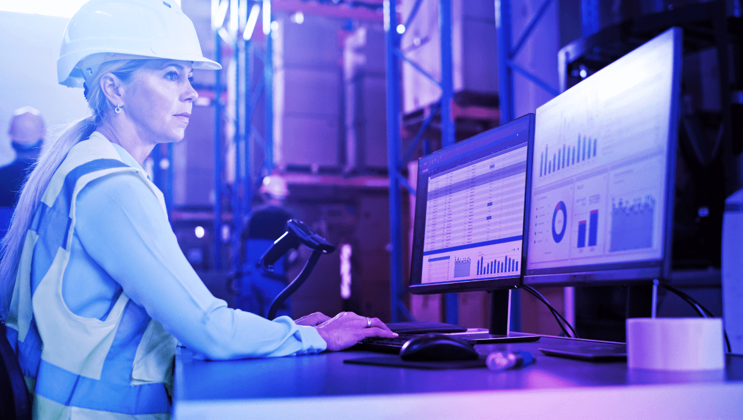 Woman wearing a hard hat in a warehouse looking at a computer as part of Crane Authentication digitized compliance solutions for product verification