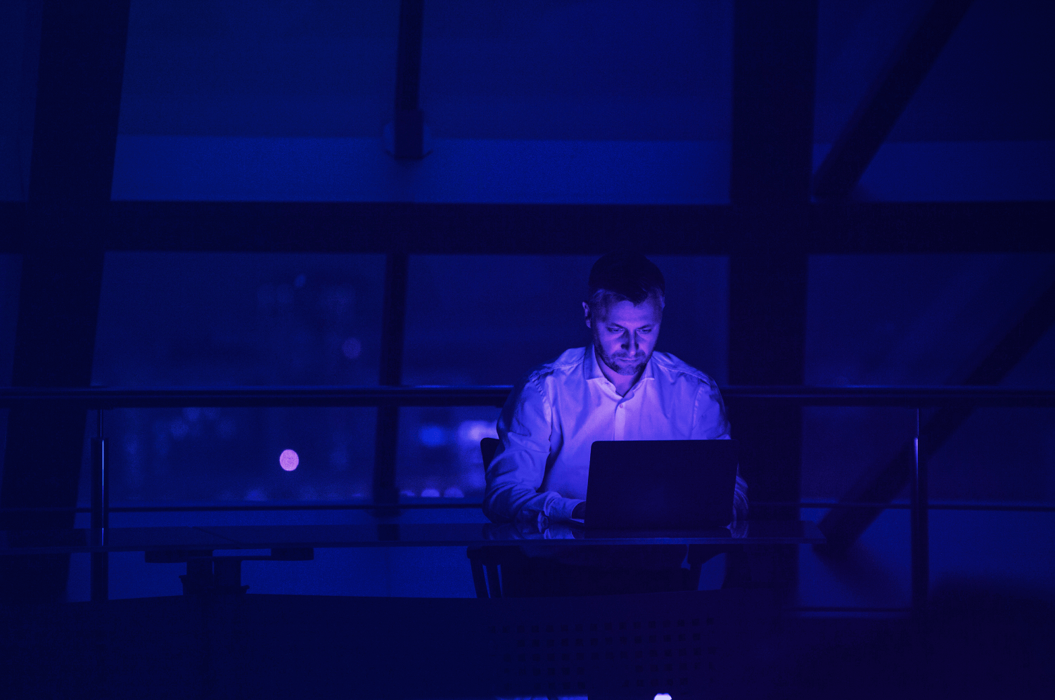 Man in a dark room working on a computer to combat fraud using Crane Authentication anti-fraud solutions